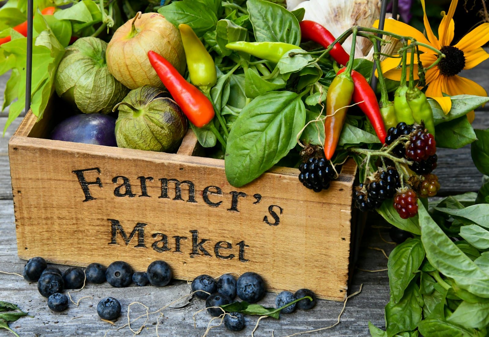 A wooden crate of fresh vegetables, herbs and berries